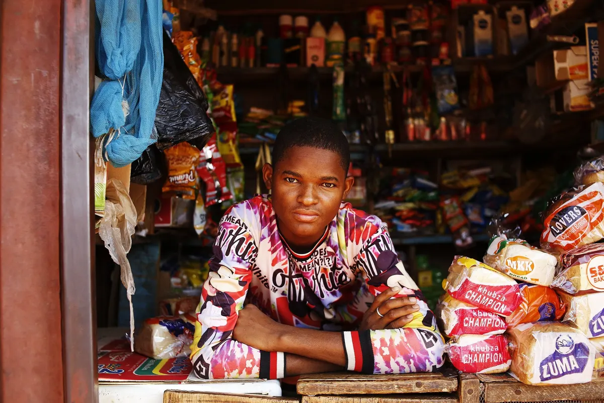 Un jeune commerçant dans sa boutique, entouré de ses produits
