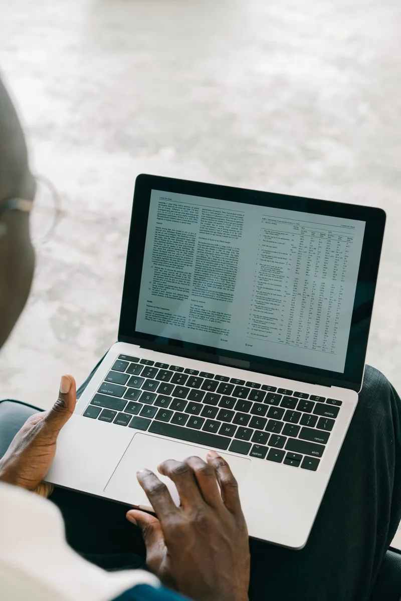 Des mains tapent sur le clavier d'un ordinateur portable affichant un tableau de données